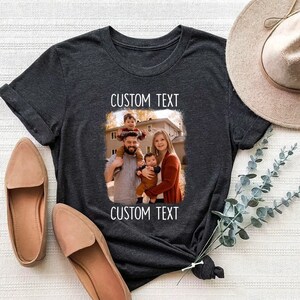 May include: A dark gray t-shirt with a photo of a family of four. The photo is in a white frame with the text "CUSTOM TEXT" above and below the photo.