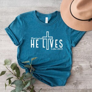 May include: Teal blue t-shirt with a white cross and the text "Plot twist He Lives" and "Luke 24:23".