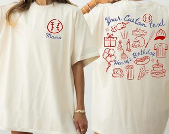 May include: Ivory t-shirt with a baseball graphic and the word "Mama" in blue. The back of the shirt features baseball-themed illustrations and the text "Your Custom text" and "Henry's Birthday" in blue.