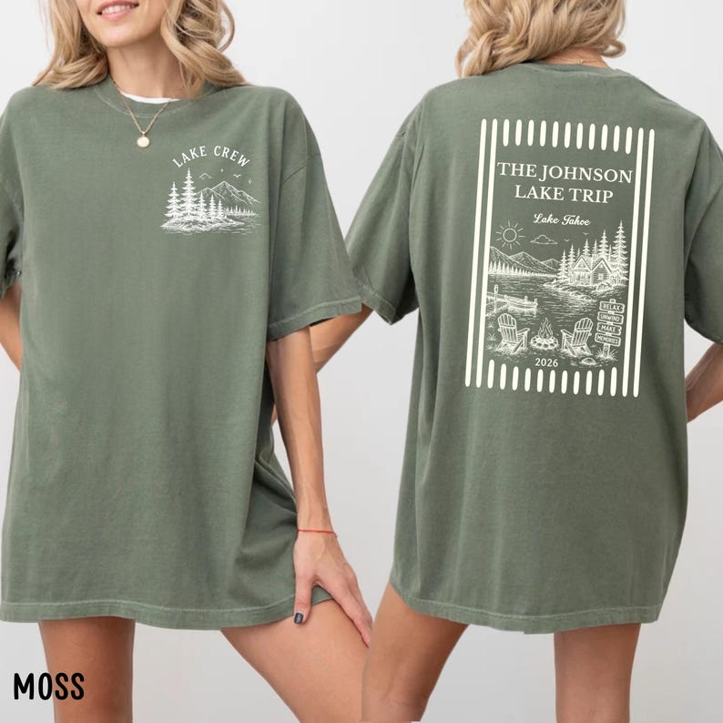 Puede incluir: Camiseta verde musgo con dise&ntilde;os gr&aacute;ficos blancos. La parte delantera presenta "Lake Crew" con una escena de monta&ntilde;a y &aacute;rboles. La parte trasera muestra "The Johnson Lake Trip Lake Tahoe 2026" con una escena de lago y sillas.
