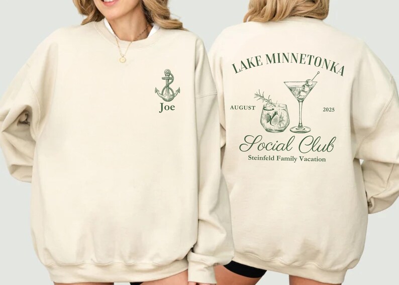 May include: Cream-colored sweatshirt with green anchor graphic and the name "Joe". The back features "Lake Minnetonka Social Club" text, cocktail illustrations, and "August 2025". Steinfield Family Vacation is also printed on the back.