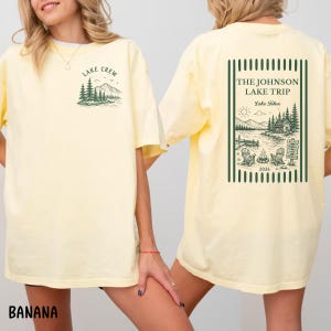 Puede incluir: Camiseta amarilla clara con el texto "LAKE CREW" y un gr&aacute;fico de monta&ntilde;a y pino en la parte delantera. La parte posterior de la camisa presenta un gr&aacute;fico enmarcado en verde con el texto "THE JOHNSON LAKE TRIP Lake Tahoe 2026".