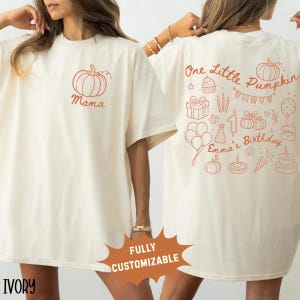 Könnte beinhalten: Ein elfenbeinfarbenes T-Shirt mit einer kleinen orangefarbenen Kürbisgrafik und dem Schriftzug Mama auf der linken Brust. Die Rückseite zeigt orangefarbene Linienzeichnungen von Kürbissen, Geschenken, Luftballons, Kuchen und dem Text One Little Pumpkin Emma's Birthday.
