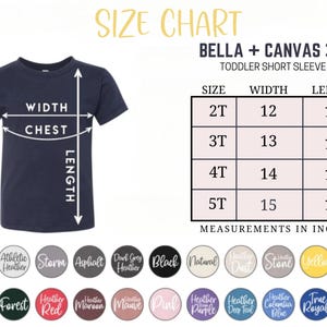 May include: Navy blue toddler short sleeve tee shirt with a size chart. The chart shows measurements in inches for sizes 2T to 5T. The width ranges from 12 to 15 inches, and the length ranges from 15 to 18 inches. The shirt is a Bella + Canvas 3001T.