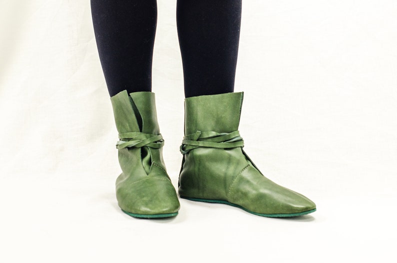 May include: A pair of green leather ankle boots with laces tied around the ankles.