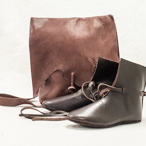 May include: Two pairs of brown leather boots with laces and a brown leather bag with a strap.