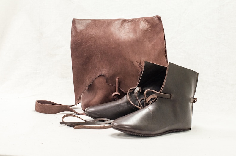 May include: Two pairs of brown leather boots with laces and a brown leather bag with a strap.