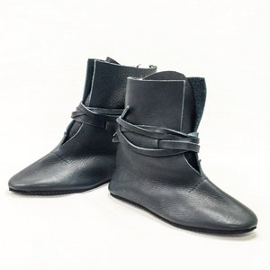May include: A pair of dark blue leather ankle boots with laces that wrap around the ankle.