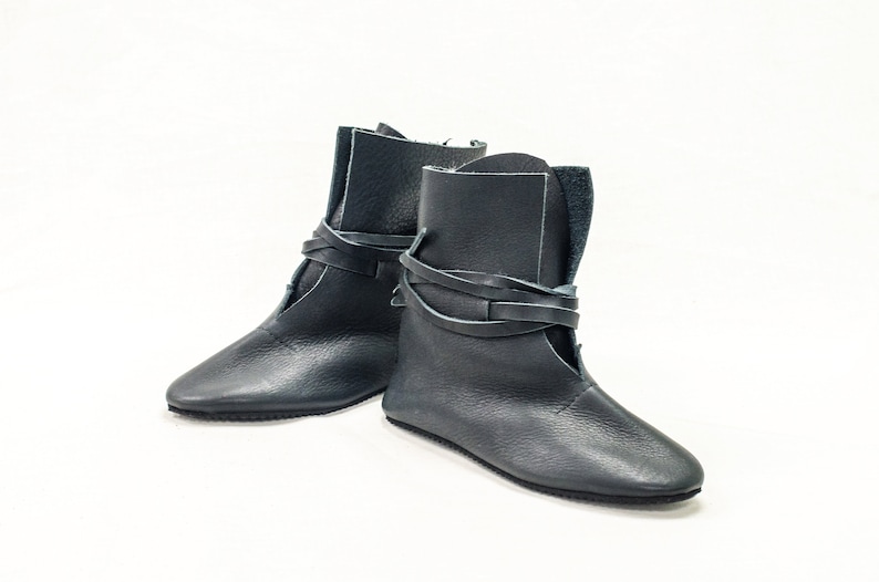 May include: A pair of dark blue leather ankle boots with laces that wrap around the ankle.