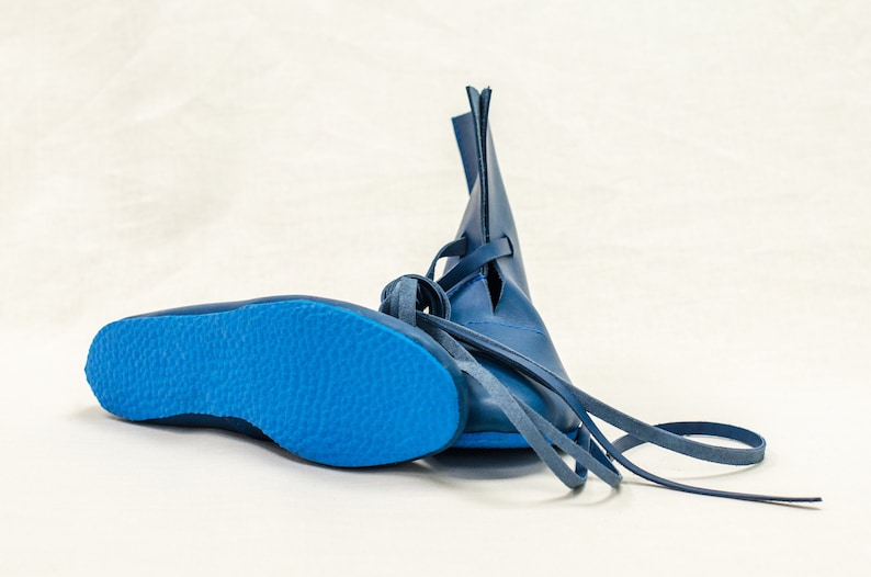 May include: A pair of blue leather boots with laces. The boots have a pointed toe and a flat sole.