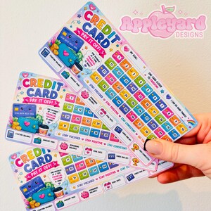 May include: Three rectangular credit card debt payoff tracker sheets with a colourful cartoon design. Each sheet features the text CREDIT CARD PAY IT OFF!, a grid of numbered squares, and illustrations of a smiling credit card, wallet, and coffee cup.