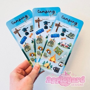 May include: Three identical light blue savings trackers titled Camping Fund, featuring a blank space for each icon value. The trackers display colourful camping-themed illustrations including a tent, campfire, backpack, camper, and hiking boots.