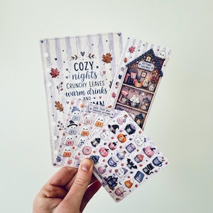May include: A collection of four autumn-themed paper inserts and sticker sheets featuring illustrations of ghosts, pumpkins, and fall foliage. The text reads COZY nights CRUNCHY LEAVES warm drinks AND AUTUMN, AUTUMN SAVINGS, and SAVE YOUR WAY THROUGH AUTUMN.