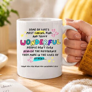 May include: A white ceramic mug with a curved handle. The mug features colorful text that reads "SOME OF LIFE'S MOST CARING, KIND, AND TRULY WONDERFUL PEOPLE DON'T EVEN REALISE THE DIFFERENCE THEY MAKE IN THE LIVES OF OTHERS..." and "THANK YOU FOR BEING YOU INCREDIBLE SELF."