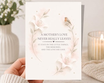 Puede incluir: Una tarjeta de felicitación con el texto "A Mother's Love Never Really Leaves". Presenta ilustraciones de lirios blancos, un pequeño pájaro y estrellas doradas. La tarjeta está en una mano.