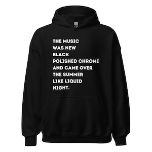 Peut inclure: Sweat-shirt à capuche noir avec un texte blanc qui dit "THE MUSIC WAS NEW BLACK POLISHED CHROME AND CAME OVER THE SUMMER LIKE LIQUID NIGHT."