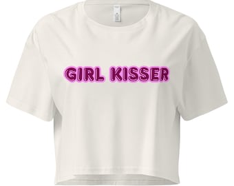 Może przedstawiać: Biały crop top z napisem "GIRL KISSER" w różowej czcionce bąbelkowej. Koszulka ma krótkie rękawy i okrągły dekolt. Tekst jest wyśrodkowany na przodzie ubrania.