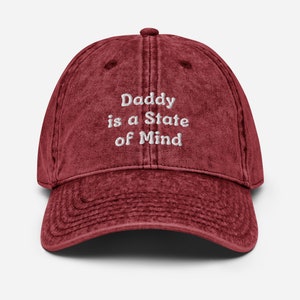 Puede incluir: Una gorra de béisbol de estilo vintage de color granate con texto bordado en blanco que dice "Daddy is a State of Mind".