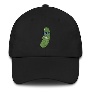 Op de afbeelding: Zwarte baseballpet met een geborduurde groene augurk die een zonnebril draagt. De augurk glimlacht en heeft zijn armen gekruist.