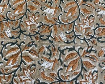 May include: A beige fabric with a repeating pattern of brown and black floral designs. The flowers are stylized and have a white center.