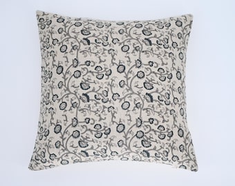 May include: A cream-colored throw pillow with a black and white floral pattern. The pillow is made of a soft, textured fabric.