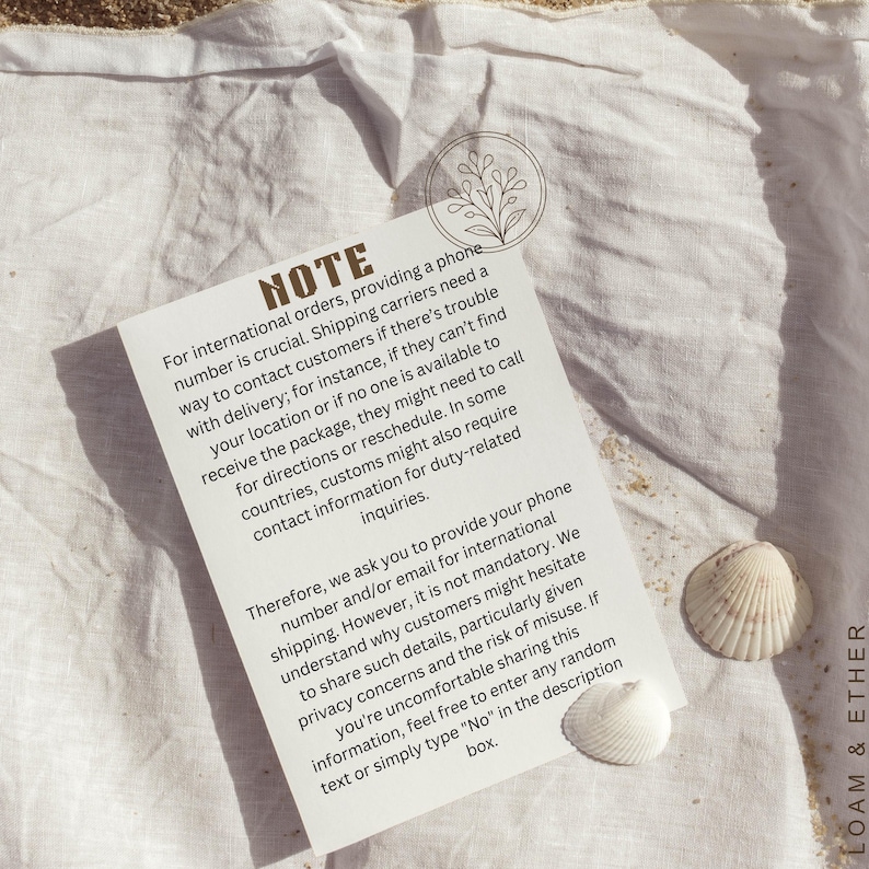 May include: A white card with the word "NOTE" printed at the top, with text about international orders and contact information. Two seashells are next to the card on a white cloth.