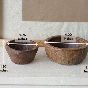 May include: Two small, rustic wooden bowls. The smaller bowl is 2.75 inches wide and 1.50 inches tall. The larger bowl is 4.00 inches wide and 1.60 inches tall. Both bowls have a natural wood grain finish and are set against a neutral background.