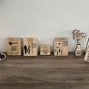 May include: A set of eight wooden signs with QR codes and text. The signs feature phrases like "Starbucks, what do you hear?", "Tell me about the wifi, George", "Do you want Wifi because this is how you get Wifi", and "Welcome".
