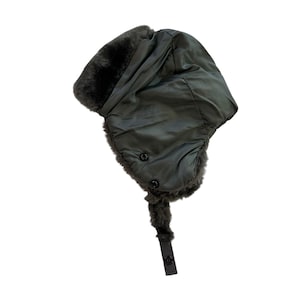 May include: A dark green aviator hat with faux fur trim and ear flaps. The hat features two black buttons and a chin strap with a snap closure. The hat is made of a smooth, possibly nylon, material.