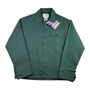 May include: A dark green work jacket with a full zipper closure, a collared neckline, and a chest pocket. The jacket has two front pockets and buttoned cuffs. A tag with the text "BIG BILL" is attached to the collar.