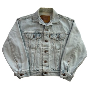 May include: Light blue denim jacket with button closures, two chest pockets, and two side pockets. The jacket has a classic collar and a faded appearance. The Levi's brand label is visible on the back of the collar.