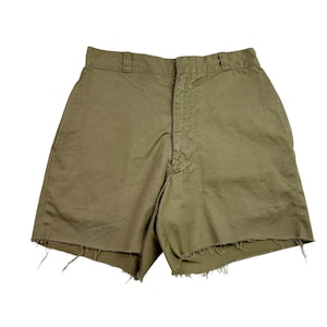 May include: Olive green shorts with a frayed hem. The shorts have a classic design with a button and zip closure, belt loops, and pockets. The shorts are made of a durable fabric.