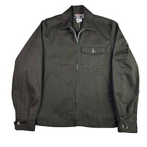May include: A dark olive green work jacket with a full zip and a collared neckline. The jacket features a single chest pocket with a button and two side pockets. The sleeves have buttoned cuffs. The jacket is made of a durable fabric, suitable for work.
