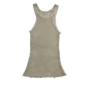 Può includere: Un top senza maniche beige a trama aperta con ampie spalline. Il capo ha una costruzione ampia, simile a una rete, e un orlo inferiore leggermente svasato. Il top è realizzato in un materiale morbido e dai toni neutri, adatto per la stratificazione o il clima caldo.