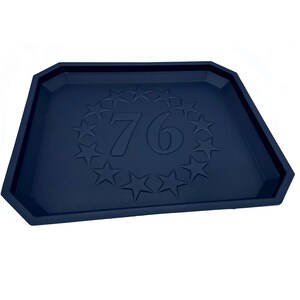 May include: A dark blue plastic tray with a raised design of a circle of stars surrounding the number "76".