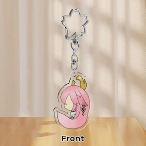 May include: A clear acrylic keychain featuring a pink anime character with a gold accent. The keychain has a silver flower-shaped clasp and a silver chain. The word "Front" is printed at the bottom.