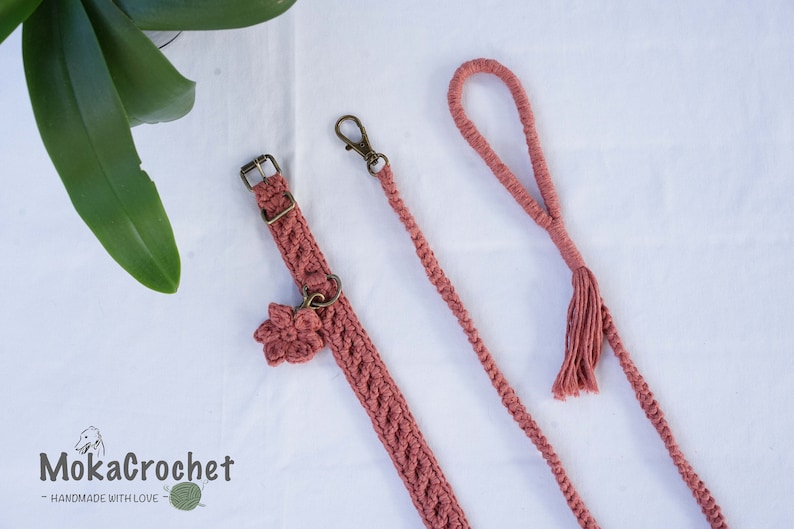 May include: A set of pink crocheted dog collar and leash with a flower charm on the collar. The leash has a tassel at the end. The text "MokaCrochet - HANDMADE WITH LOVE" is visible in the bottom left corner of the image.