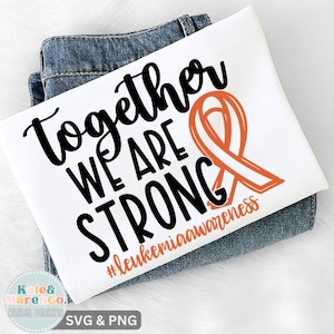 Peut inclure: T-shirt blanc avec l'inscription "Together We Are Strong" en noir et un ruban orange de sensibilisation. La phrase "#leukemiaawareness" est en dessous. Le t-shirt est plié sur un jean bleu.