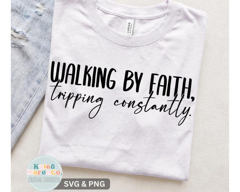 Op de afbeelding: Een wit T-shirt met korte mouwen en de zwarte opdruk Walking by faith, tripping constantly. Het shirt heeft een ronde hals en een standaard pasvorm, waarbij de tekst wordt weergegeven in een combinatie van dikke blokletters en cursief schrift.