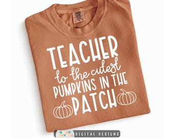 May include: A rust-colored short-sleeve t-shirt featuring white screen-printed text that reads TEACHER to the cutest PUMPKINS IN THE PATCH, accompanied by two white line-art pumpkin illustrations at the bottom of the graphic design.