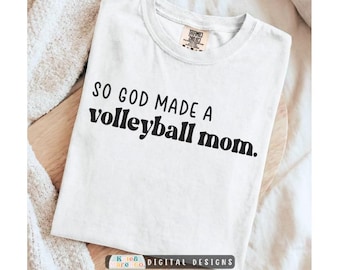 Pode incluir: Uma t-shirt branca de manga curta com texto preto impresso na frente que diz: "SO GOD MADE A volleyball mom." A peça apresenta uma gola redonda e uma etiqueta no interior da gola com a marca Comfort Colors visível no tecido.
