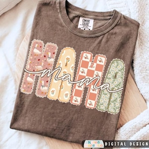 May include: A brown short-sleeve t-shirt featuring the word MAMA in large, scalloped-edge block letters. Each letter has a unique pattern: ducks on pink, floral on yellow, checkered on orange, and daisies on green. The word mama is written in white.