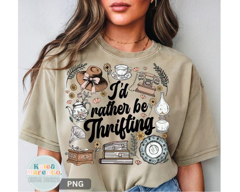 May include: Tan t-shirt with the phrase "I'd rather be thrifting" in black script. The shirt features vintage-style illustrations of a hat, teapot, telephone, books, and other antique items. The shirt is a neutral color.