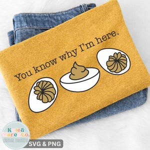 May include: A mustard yellow t-shirt featuring the black text You know why I'm here. and a graphic illustration of three deviled eggs with white egg whites and brown yolks, layered over a pair of blue denim jeans.