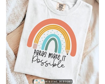 Può includere: Una t-shirt bianca con la grafica di un arcobaleno disegnato come una matita e il testo "Paras make IT Possible" stampato in nero sotto il disegno. La maglietta presenta un'etichetta del marchio Comfort Colors sul collo con taglia M.