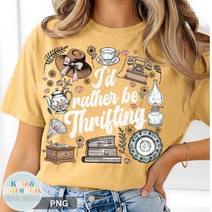 May include: Mustard yellow t-shirt with the phrase "I'd rather be thrifting" and vintage-style illustrations of a hat, teapot, teacup, telephone, lamp, plate, books, and a gramophone.