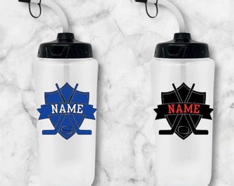 May include: Two clear plastic water bottles with black lids and blue and black hockey stick and puck designs. The bottles have a straw and the text "NAME" is on the design.