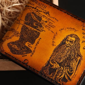 May include: A brown leather wallet with a map of Middle-earth from The Lord of the Rings. The map includes the text "Mirkwood" and "East Bight". The wallet also features a portrait of Gandalf the Grey with the quote "All we have to decide is what to do with the time that is given us."