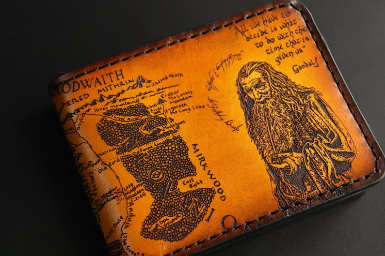 May include: A brown leather wallet with a map of Middle-earth from The Lord of the Rings. The map includes the text "CODWAITH PERED MITHRIN" and "MIRKWOOD". A quote from Gandalf is printed on the right side of the wallet: "All we have to decide is what to do with the time that is given us."