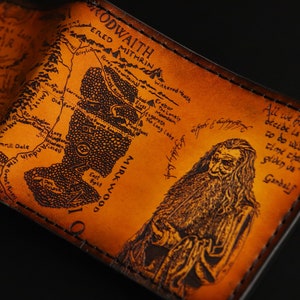 May include: A brown leather wallet with a map of Middle-earth from The Lord of the Rings and a portrait of Gandalf. The text on the wallet reads "All we have to decide is what to do with the time that is given us - Gandalf".